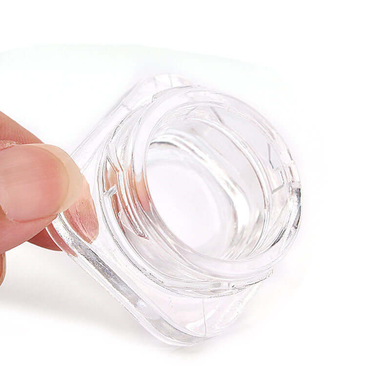 Hand holding a 5 ML square clear glass jar, showcasing crystal clarity and compact design for storage.