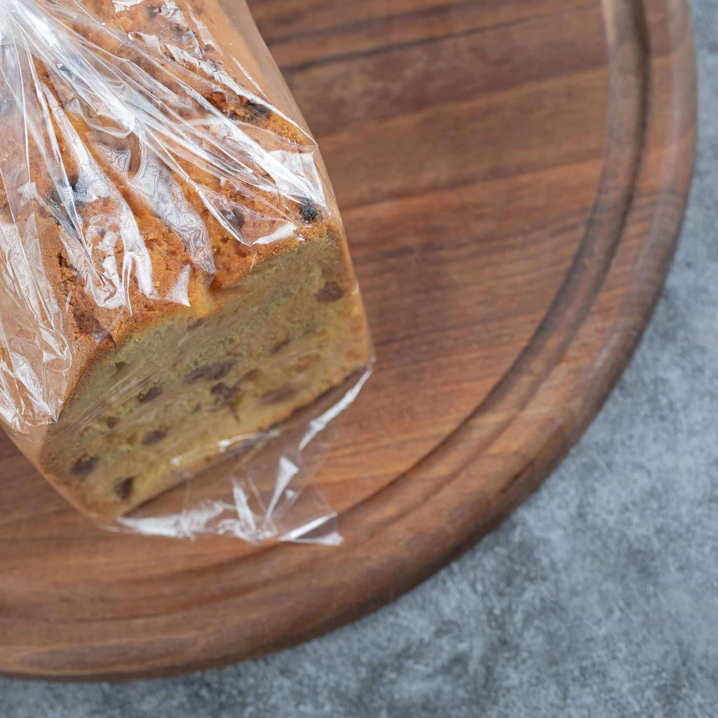 Sliced bread wrapped in a clear gusseted poly bag on a wooden board, showcasing freshness and packaging.
