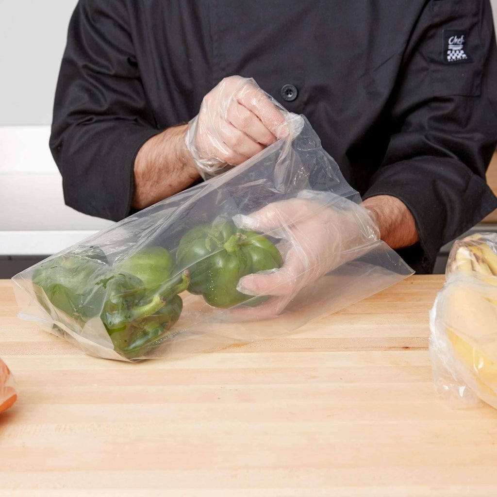 Chef using a clear gusseted poly bag to package green bell peppers on a kitchen countertop.