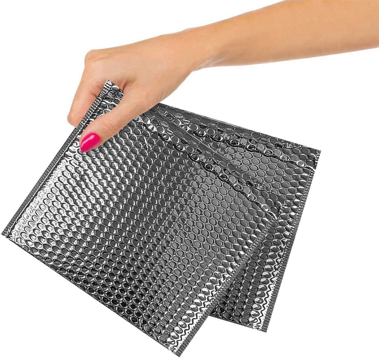 Person holding three silver metallic bubble mailers, 6 x 6.25 inches, highlighting waterproof and elegant packaging.